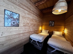 A cozy cabin room with wooden walls, two beds, a hanging light fixture, and framed artwork. - Chalet 4 bedrooms, modern comfort, Arêches-Beaufort (Arêches-Beaufort)