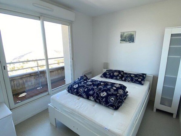 A bedroom with a bed, a window, and a small picture on the wall.