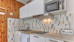 A modern kitchen with white cabinets, a wooden countertop, a built-in microwave, and a patterned backsplash. - Cozy apartment for 4 in Gourette, southwest balcony, optional services (Gourette)