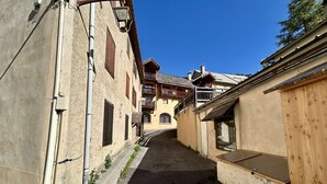 A narrow alleyway with buildings on either side, featuring balconies and wooden shutters.