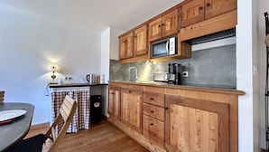 A compact kitchen with wooden cabinets, a microwave, and a coffee maker.