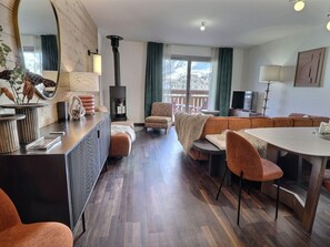 A modern living room with a fireplace, a dining area, and a large window with a view.
