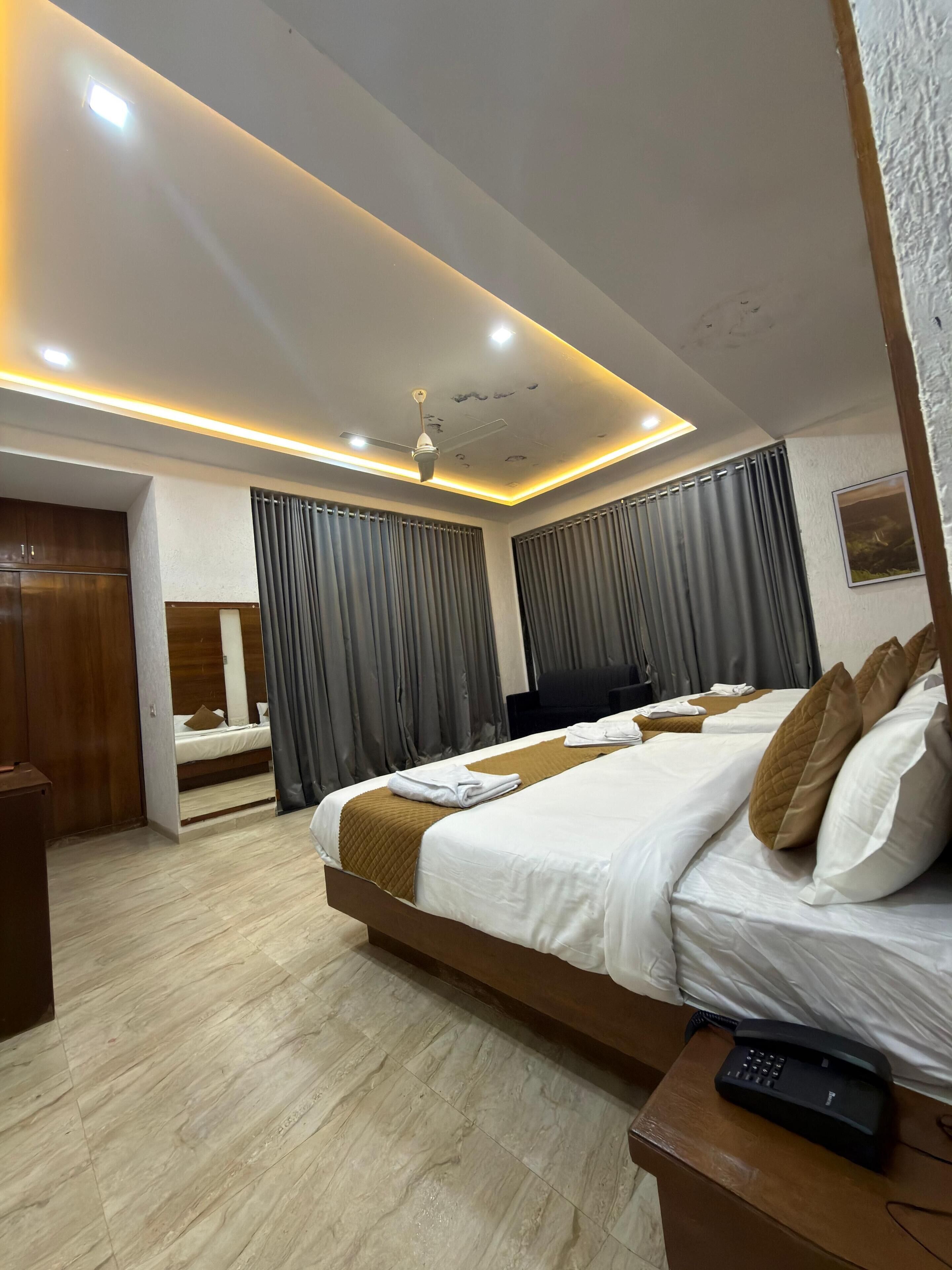 A modern hotel room with a large bed, a ceiling fan, and a bedside telephone.