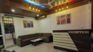 A reception area with a reception desk, a sofa, and a ceiling fan.