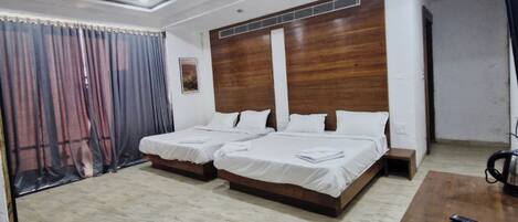 Habitación de hotel moderna con dos camas, un cabecero de madera, un escritorio y un televisor.