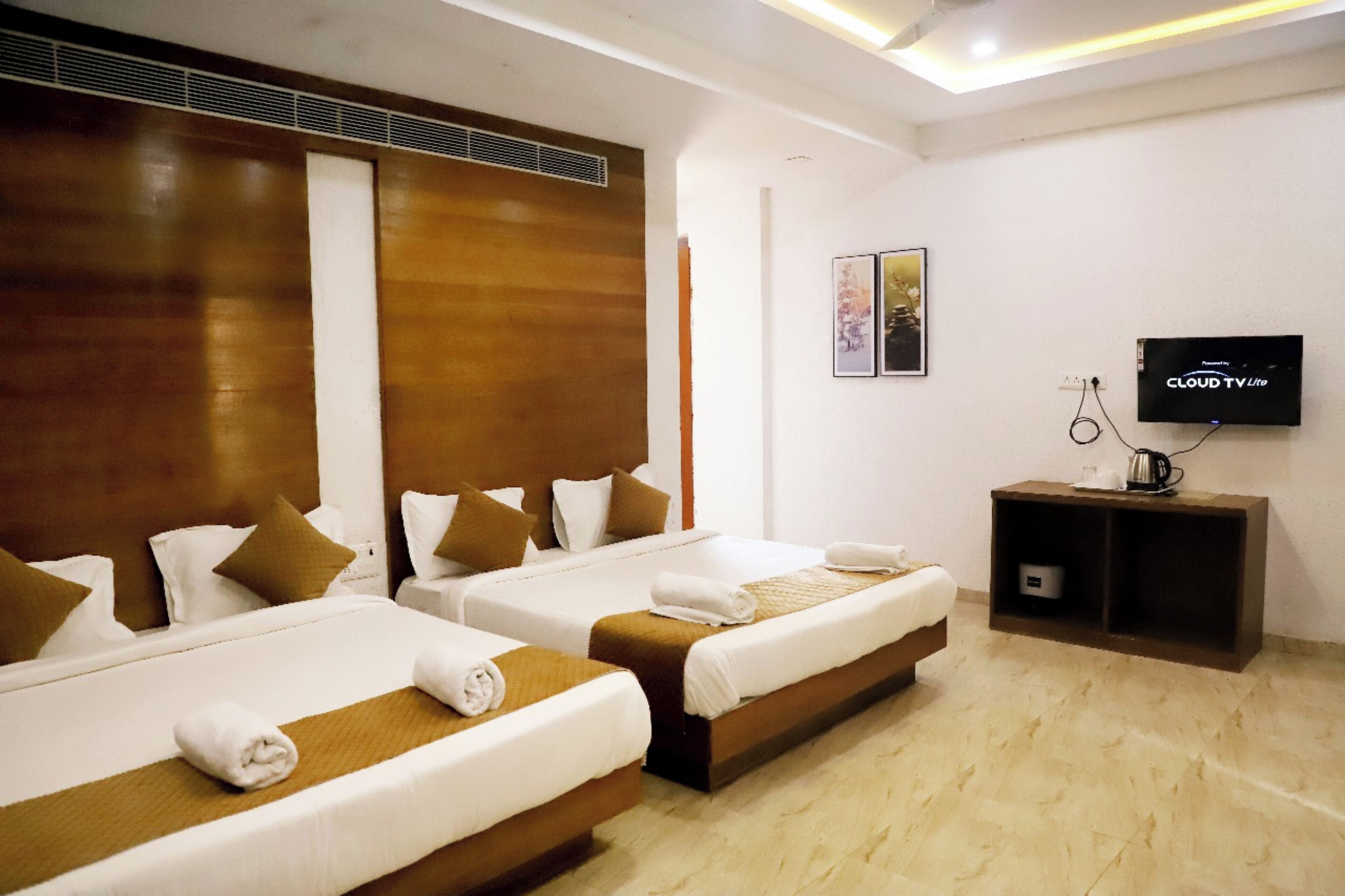 A hotel room with two beds, a TV, and a small cabinet.