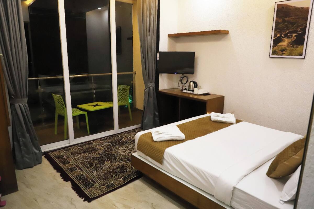Une chambre d’hôtel comprenant un lit, un bureau avec un téléviseur à écran plat, une chaise, une fenêtre avec des rideaux et une vue sur un paysage.