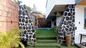 A courtyard with a stone wall, a small garden area, and a vehicle parked outside.
