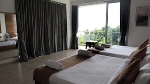A hotel room with two beds, a balcony, and a view of greenery.