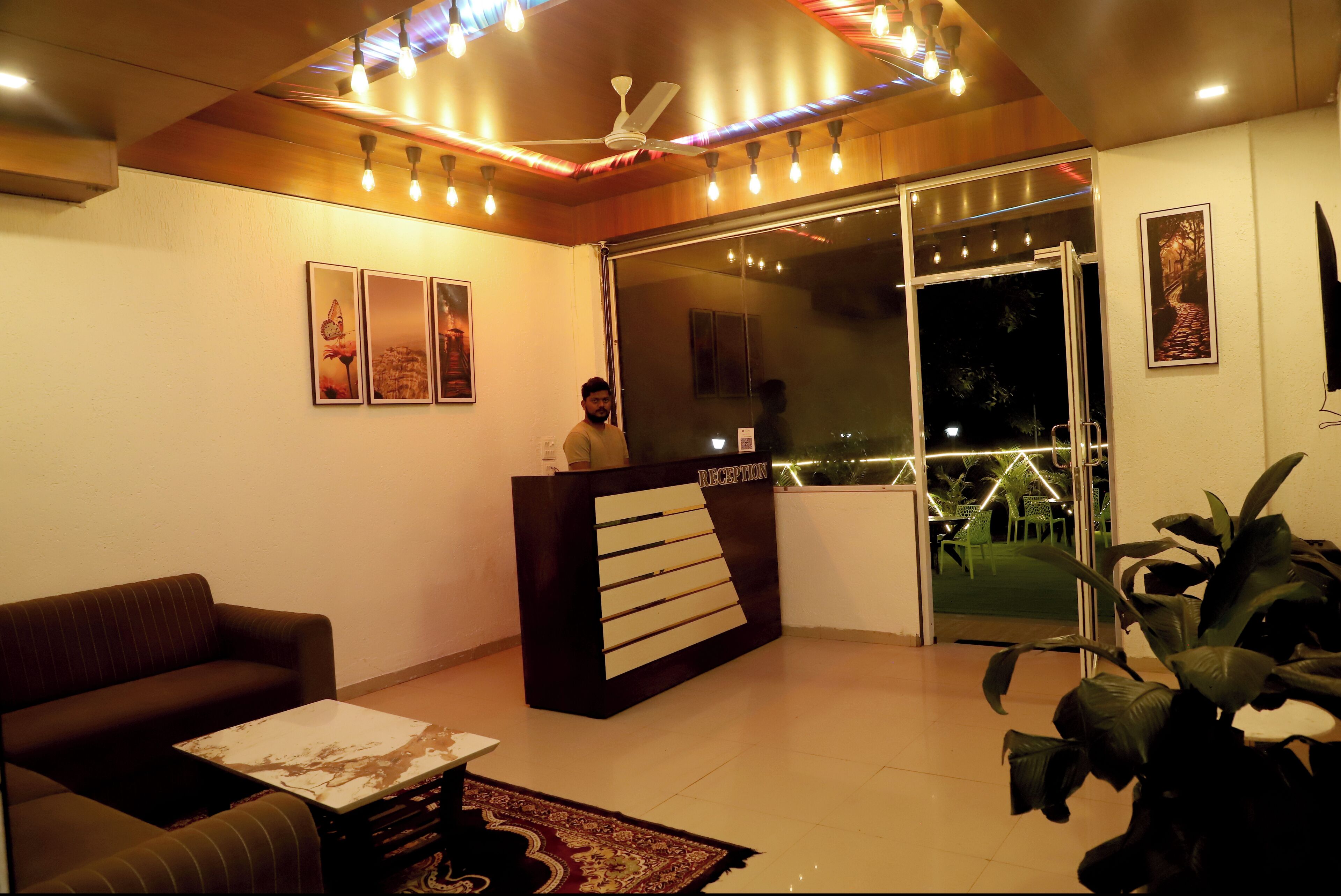A reception area with a reception desk, a sofa, a coffee table, and a large potted plant.