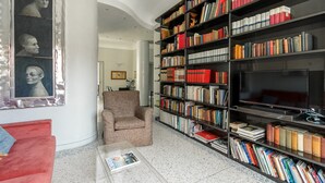 Eine Bibliothek mit Bücherregalen, einem Fernseher und einem roten Sofa.