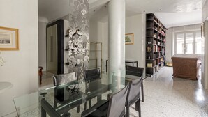 Ein modernes Wohnzimmer mit einem Glastisch, einer großen Bücherwand und einer gemütlichen Sitzecke.