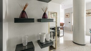 Ein modernes Interieur mit Schwarz-Gold-Dekor, darunter ein Glastisch, eine weiße Vase und eine dekorative Vase auf einem schwarzen Regal.