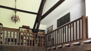 Een rustiek interieur met een stenen vloer, houten meubels, een tafel met metalen bekers en een kroonluchter.