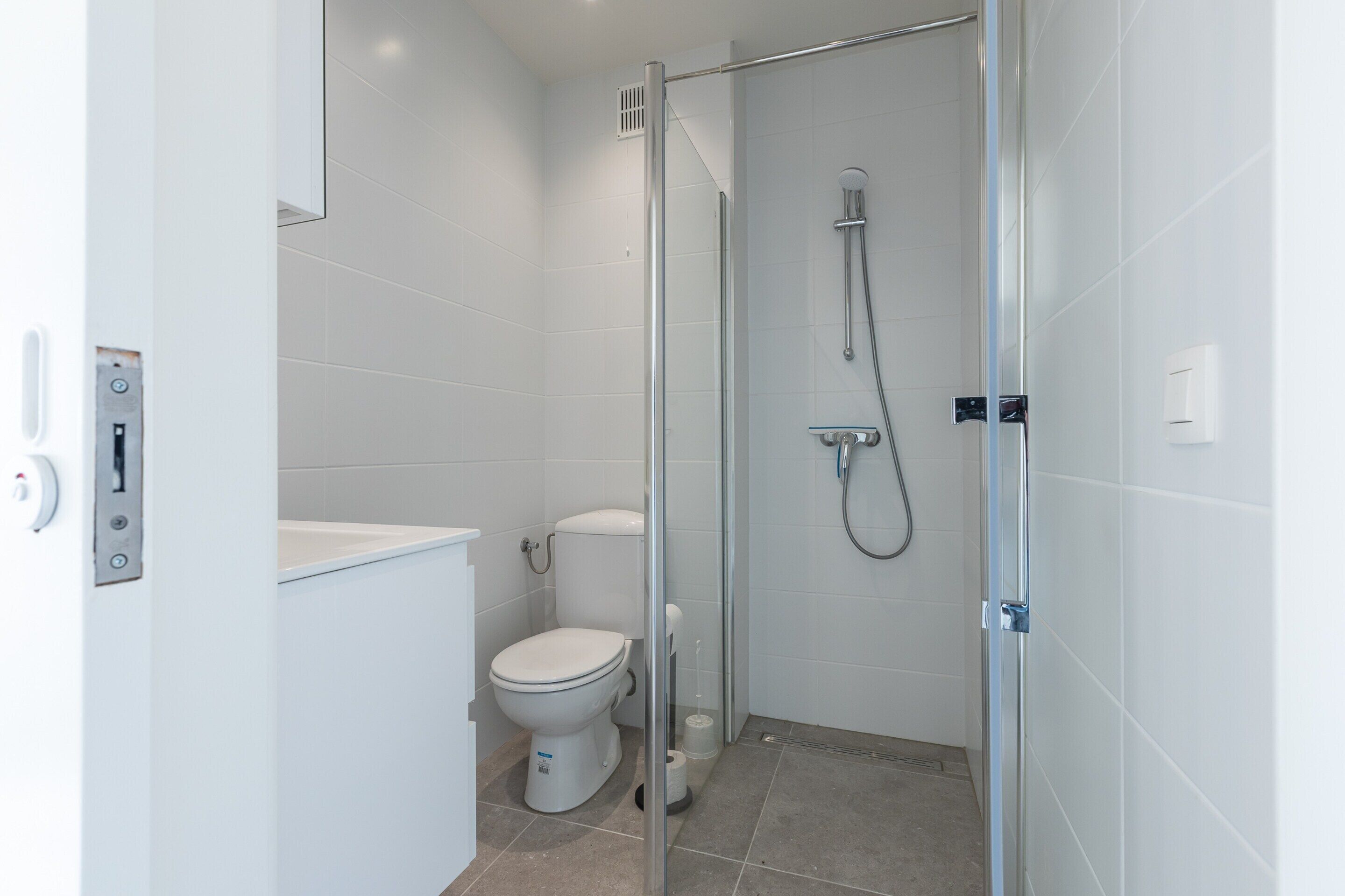 Une salle de bain moderne avec une douche à parois de verre, des toilettes et un lavabo.