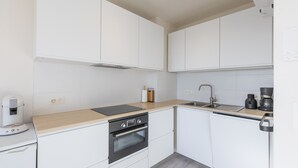 A modern kitchen with white cabinets, a wooden countertop, a built-in oven, a coffee machine, and a sink. - Modern, Renovated Studio With Open Views (Middelkerke)