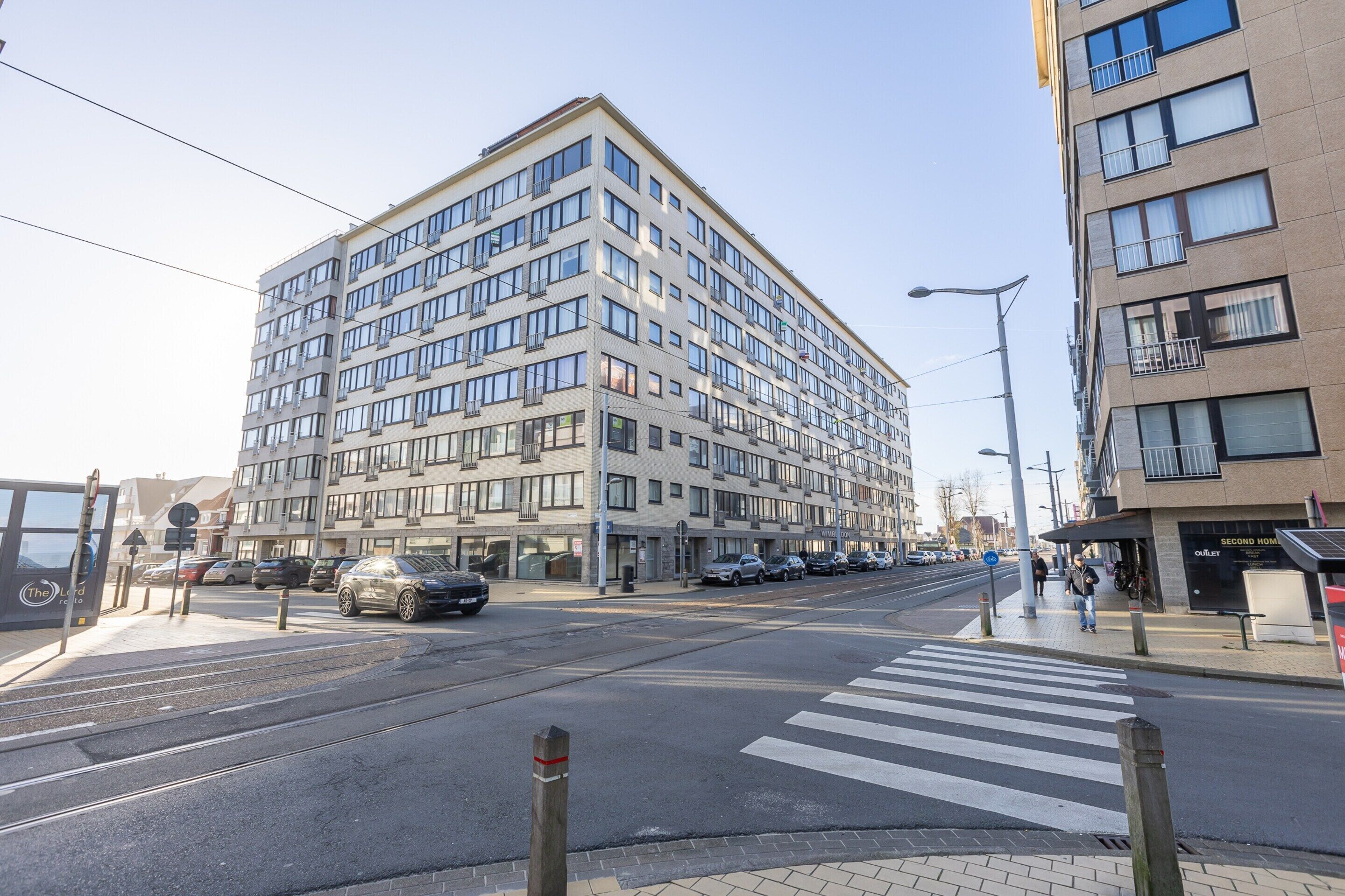 Un edificio de varios pisos con un diseño arquitectónico moderno, que cuenta con numerosas ventanas y balcones.