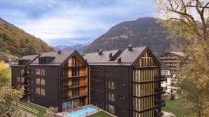 Ein modernes, mehrstöckiges Hotel mit Pool, Balkonen und einer Bergkulisse.