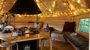 Interior acogedor de una cabaña con una mesa de comedor de madera, un banco y una chimenea.