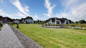 Un chemin qui mène à une zone herbeuse, avec des maisons et une clôture.