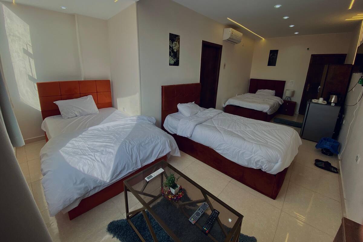 Une chambre d’hôtel avec deux lits, une petite table et un réfrigérateur.