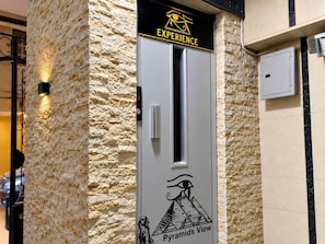A door with a stone-textured wall, a sign reading 'EXPERIENCE,' and a graphic of a pyramid with the text 'Pyramids View.' - Experieance Pyramids VIEW (Giza)