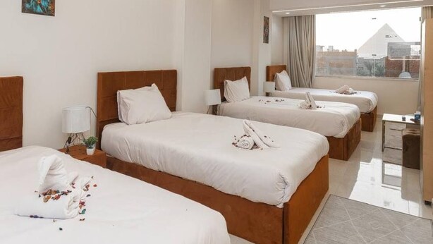 Une chambre d’hôtel avec trois lits, un bureau et une grande fenêtre.