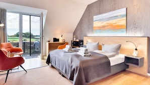 Een moderne slaapkamer met een groot bed, een bureau en een stoel. Er is uitzicht op het landschap door het raam.