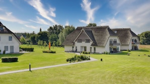 Een woonwijk met twee huizen met puntgevels en een verzorgd gazon.