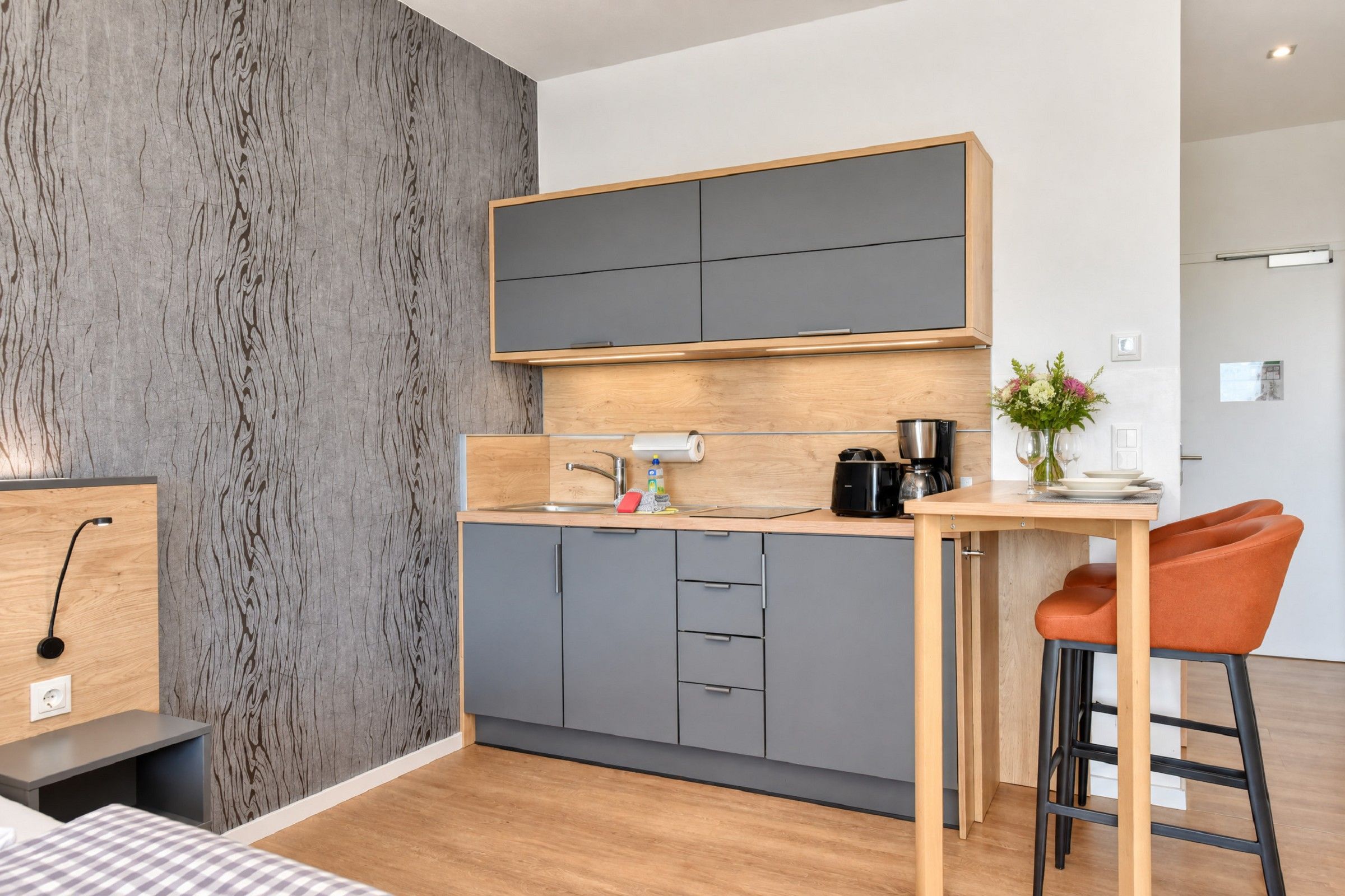Eine moderne Küche mit grauen Schränken, einer Holzarbeitsplatte, einer Kaffeemaschine und einem kleinen Spülbecken.