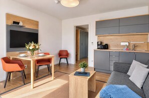 A modern living space with a dining area, a kitchen, and a seating area. - Vacation apartment in the Wreecher Idyll on Lake Wreechen (Putbus)