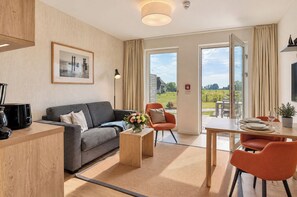 A modern living room with a sofa, coffee table, and dining area. - Vacation apartment in the Wreecher Idyll on Lake Wreechen (Putbus)