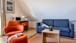 En moderne stue med en blå sofa, en orange lænestol og et lille træbord.