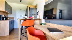 A modern kitchen with wooden cabinets, a dining area with a laptop, and a large window. - Vacation apartment in the Wreecher Idyll on Lake Wreechen (Putbus)