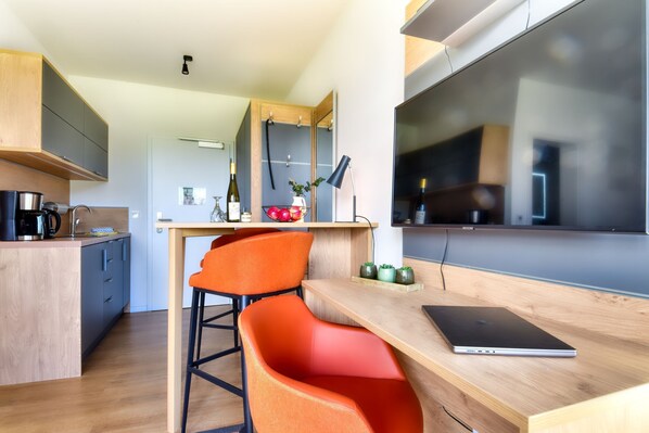 Eine moderne Küche mit Holzausstattung, ein Essbereich mit einem Laptop und ein großes Fenster.
