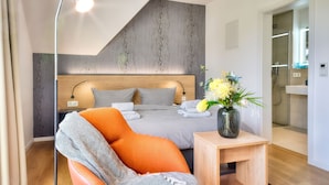 A modern bedroom with a bed, a chair, a bedside table, and a lamp. - Vacation apartment in the Wreecher Idyll on Lake Wreechen (Putbus)