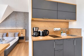 Ein modernes Schlafzimmer mit Bett, Nachttisch und einer Ablage. Das Zimmer verfügt über eine schräge Decke und ein Holz-Kopfteil.