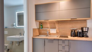 Una cocina moderna con un lavamanos, encimera, armarios y una cafetera.