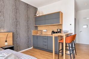 Une cuisine moderne avec des meubles gris, un plan de travail en bois et un petit îlot central doté de tabourets de bar.