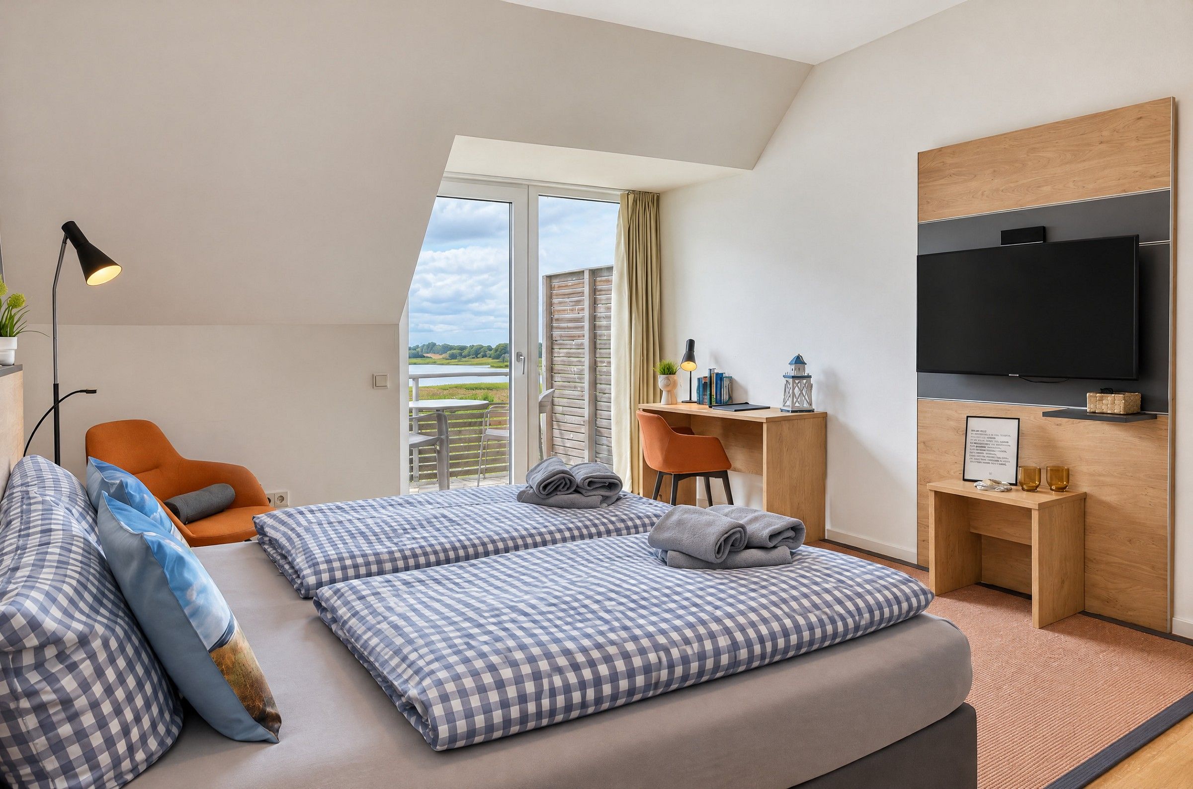 Ein Hotelzimmer mit einem Bett, einem Schreibtisch, einem Sessel, einem Fernseher und Blick ins Freie.