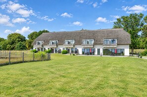 A modern building with a flat roof and multiple balconies, surrounded by a well-maintained lawn. - Vacation apartment in the Wreecher Idyll on Lake Wreechen (Putbus)