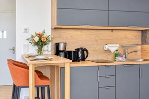 A compact kitchen with a wooden countertop, a coffee maker, a kettle, and a sink.