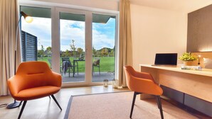 A modern room with two orange chairs, a wooden desk with a laptop, and a large sliding glass door leading to an outdoor area. - Vacation apartment in the Wreecher Idyll on Lake Wreechen (Putbus)