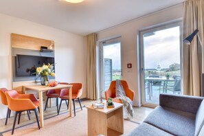 Relax in a spacious room with a comfortable seating area, flat-screen TV, and sliding glass door to a balcony with countryside views.