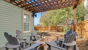 Eine Holzterrasse mit Adirondack-Stühlen und einem Tisch, umgeben von einem Holzzaun und Bäumen.