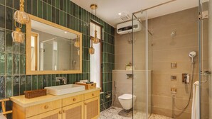 Un baño moderno con un espejo grande, tocador de madera y cabina de ducha con mampara de vidrio.