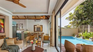 Una sala de estar moderna con vista a la piscina, que incluye un sofá, una mesa de centro, sillas de mimbre y un comedor.