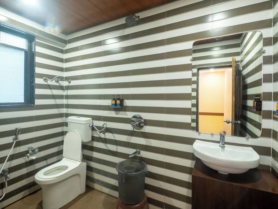 Un baño con paredes a rayas, un inodoro, un lavamanos, una ducha y un espejo.