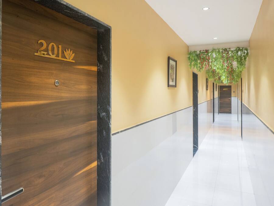 A hallway with a wooden door labeled "201" and a modern interior with a tiled floor and a green plant hanging from the ceiling.