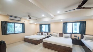 Habitación de hotel con dos camas, ventilador de techo, equipo de aire acondicionado y vista al exterior.